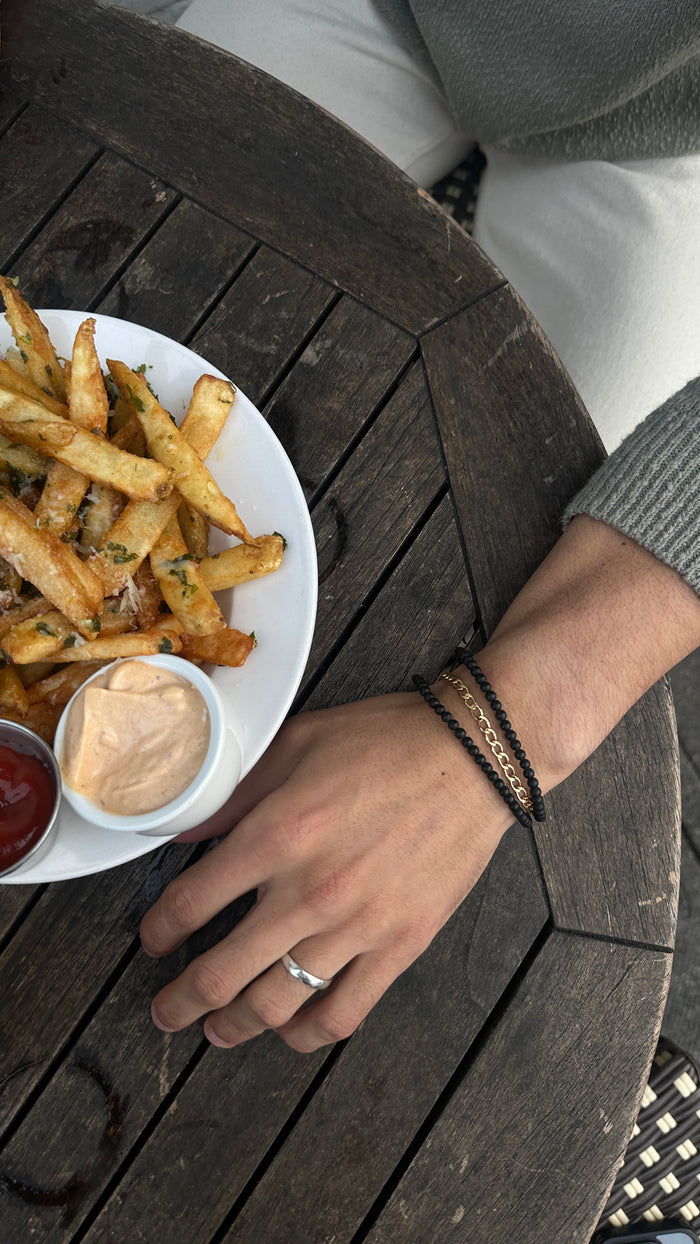 A person's arm in a grey sweater, resting on a table with food