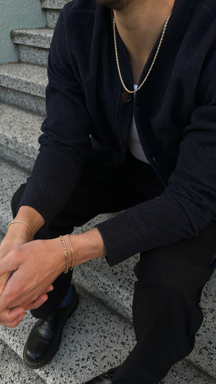 A person sitting on a staircase wearing black clothing and gold jewelry