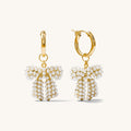 Close up of gold huggie earrings with removable charms on a white background