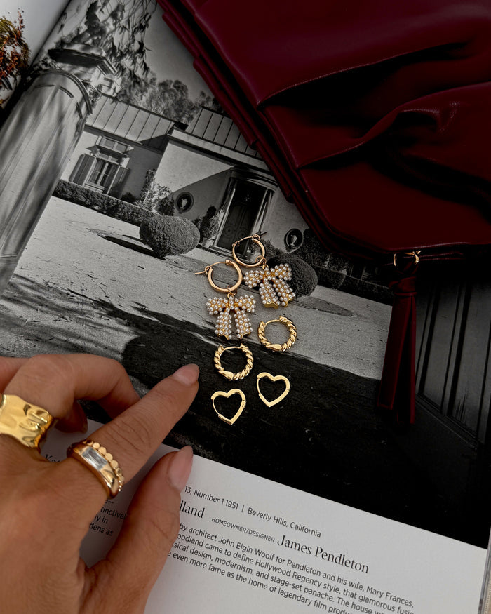 Three pairs of statement hoop earrings on a magazine background with a red purse