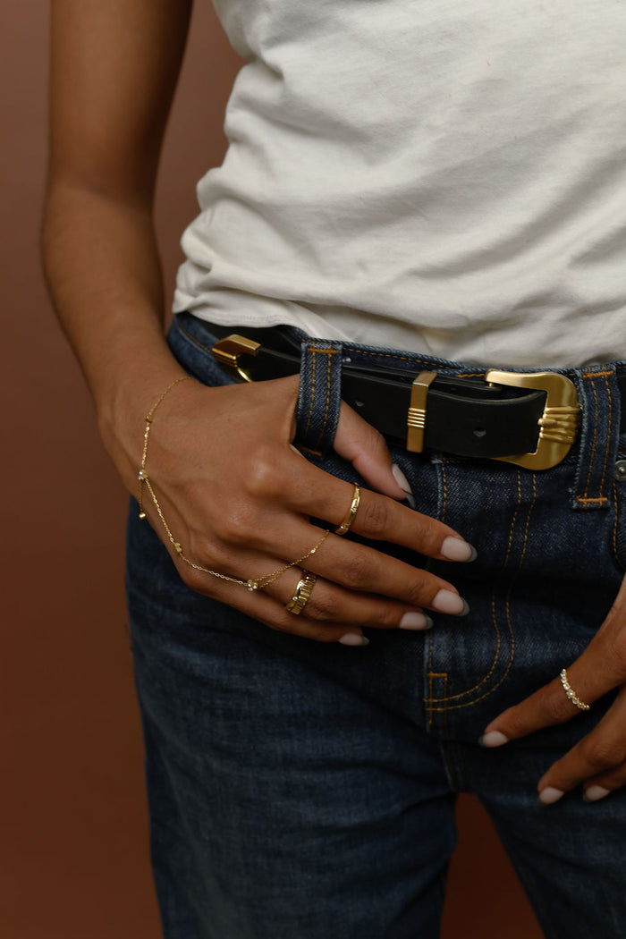 Close up of person wearing a white shirt, blue jeans, and gold rings