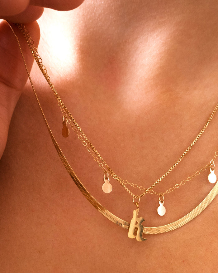 Love Letters initial pendant hanging on a light-reflecting box chain
