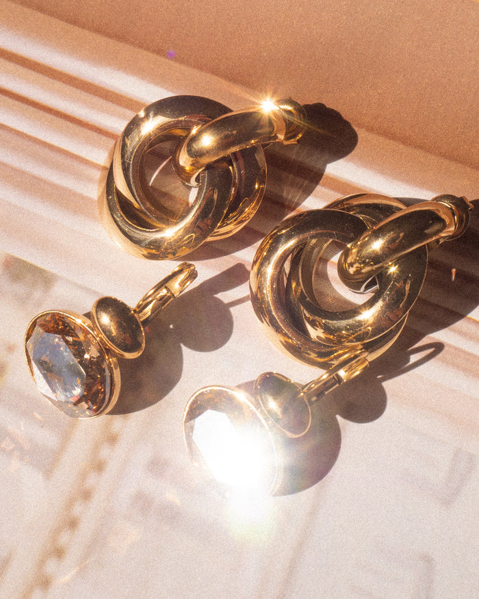 Two pairs of gold statement earrings on a jewelry case