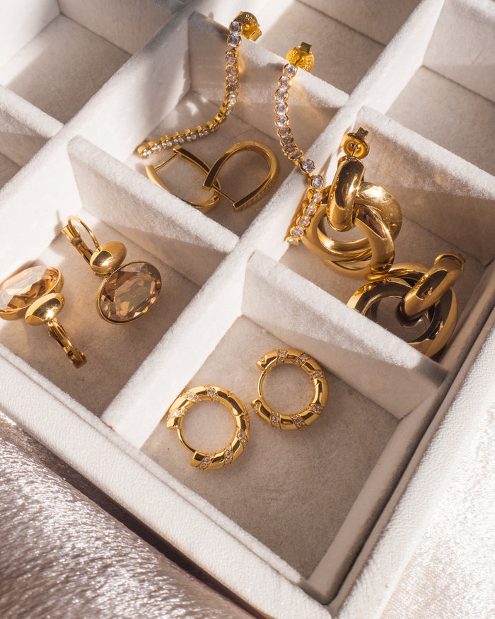 Pairs of gold earrings in a white jewelry organizer