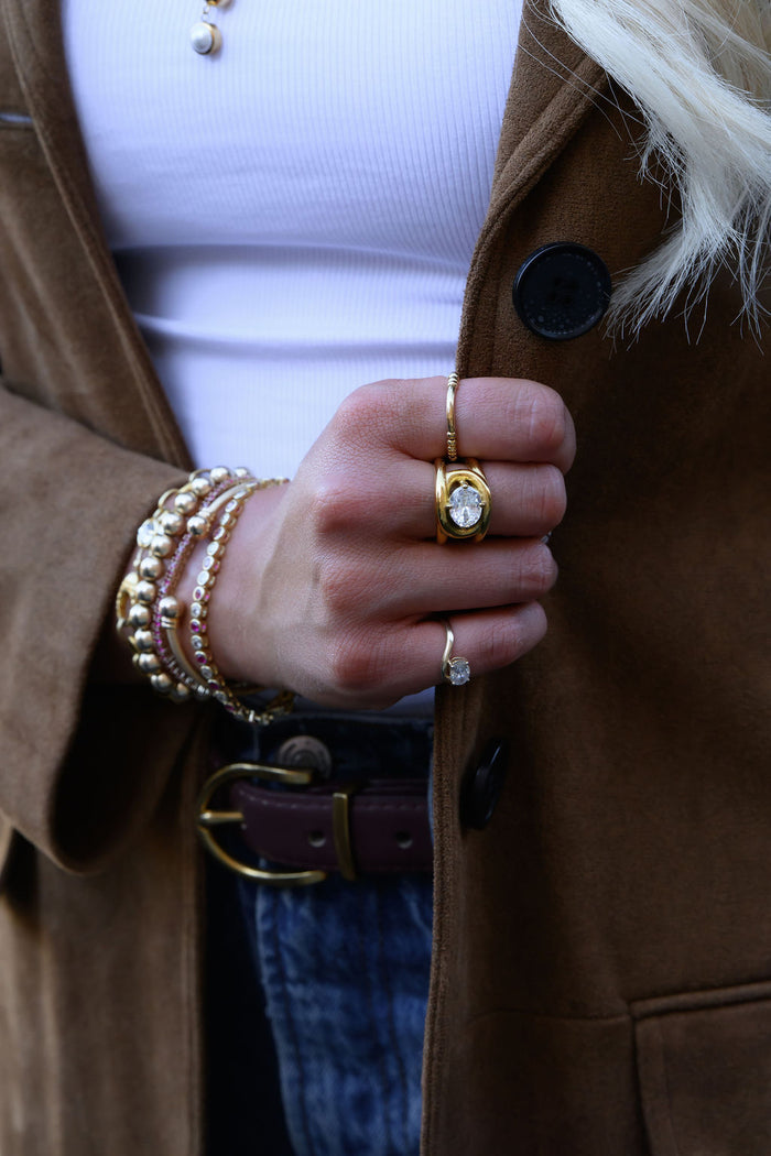 The Luma ring, gold beads on a stretch band with a curved bar detail