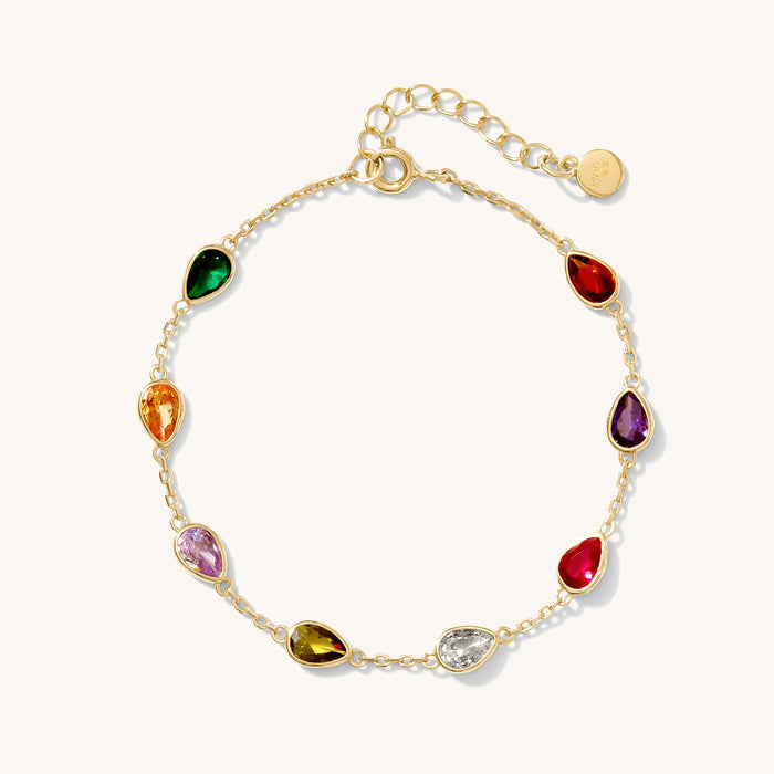 Close up of a gold bracelet with colored stones on a white background