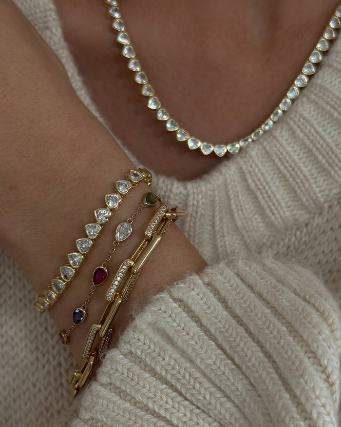 Close up of a person wearing a white sweater with gold and stone jewelry