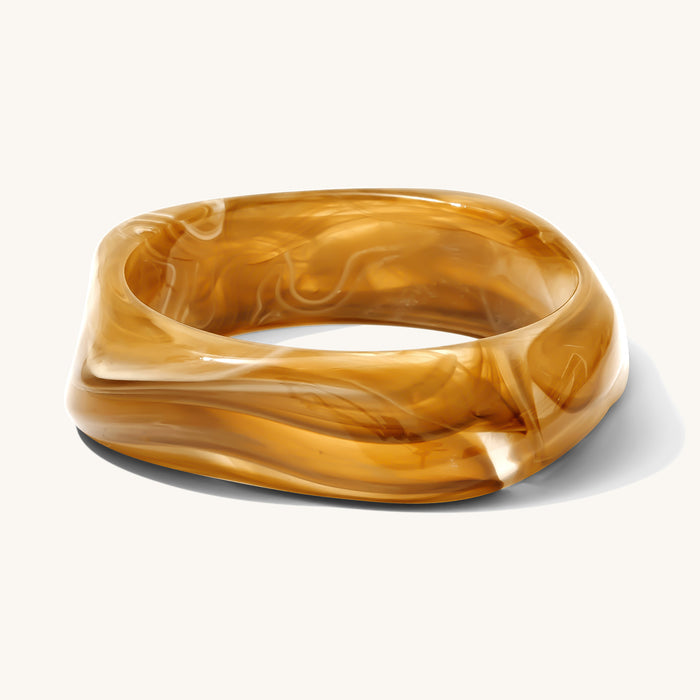 Close up of brown resin bangle on a white background