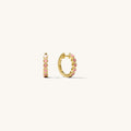 Close up of gold hoops with pink accents on a white background