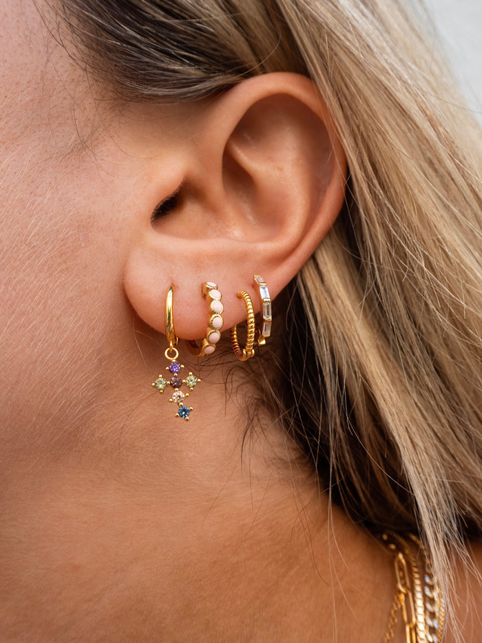 Close-up of an ear with multiple gold hoop earrings