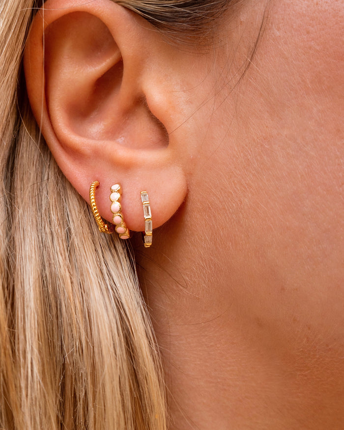 Close-up of an ear with multiple gold hoop earrings