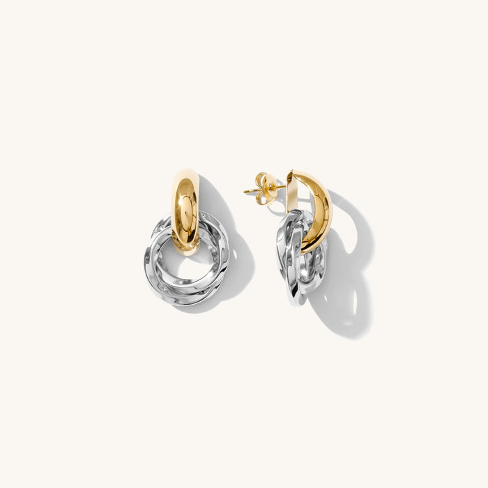 Close up of mixed metal knocker earrings on a white background