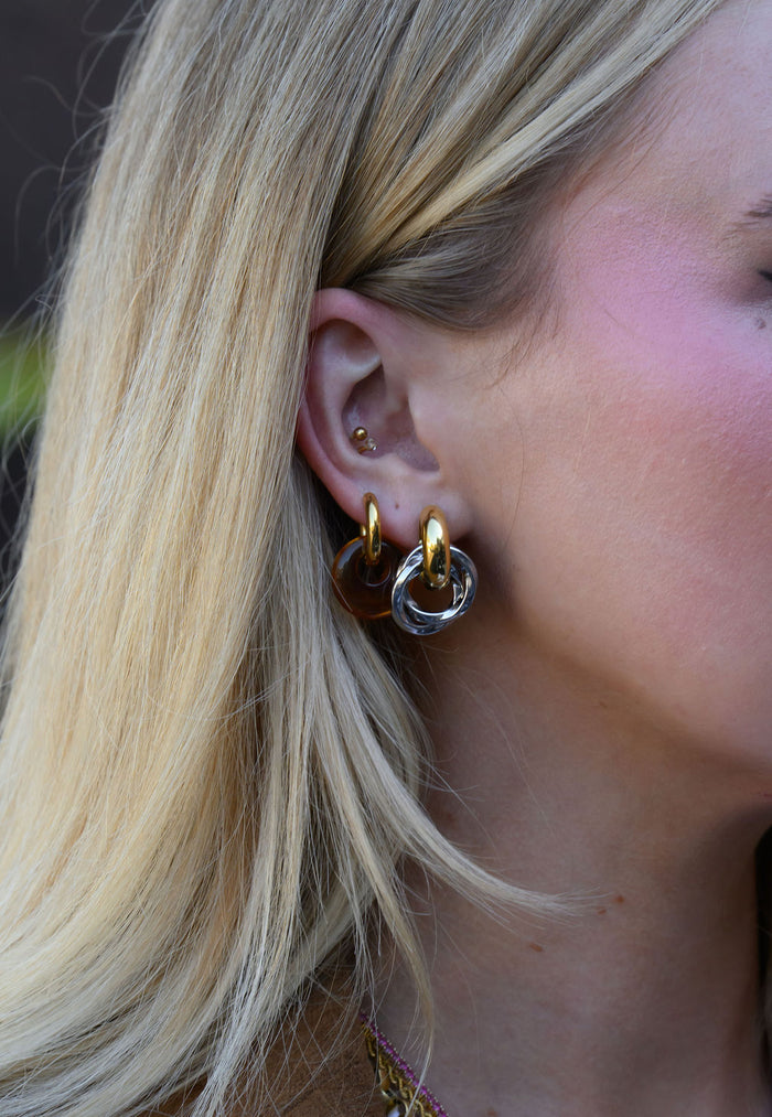 Close-up side view of a woman wearing mixed metal earrings