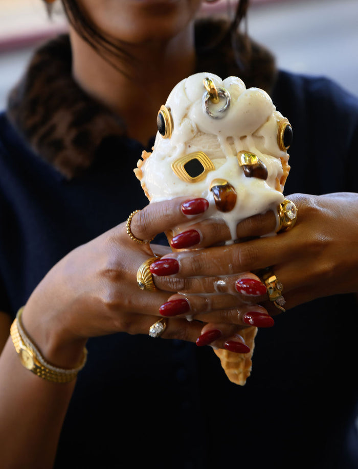 A woman holding an ice cream cone with various gold earrings on top