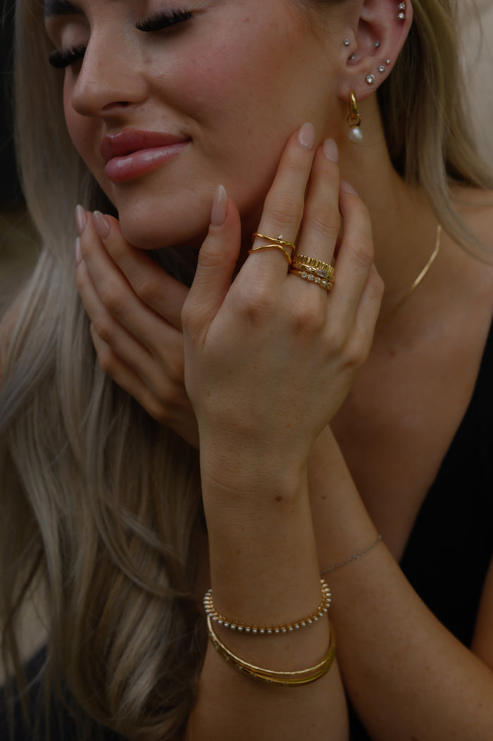 A woman holding up her hands showing gold bracelets