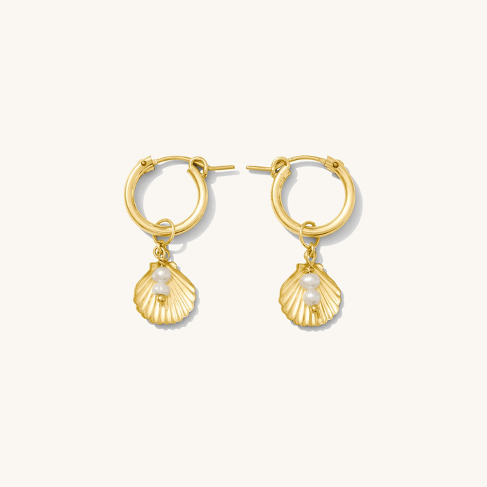 Close up of gold huggie earrings with removable charms on a white background
