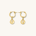 Close up of gold huggie earrings with removable charms on a white background