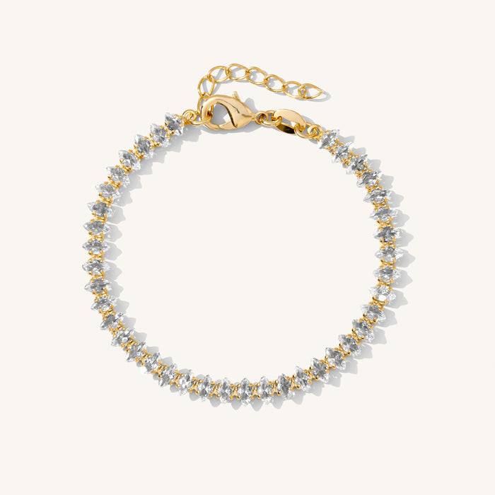 Close up of a gold tennis bracelet with marquise stones on a white background