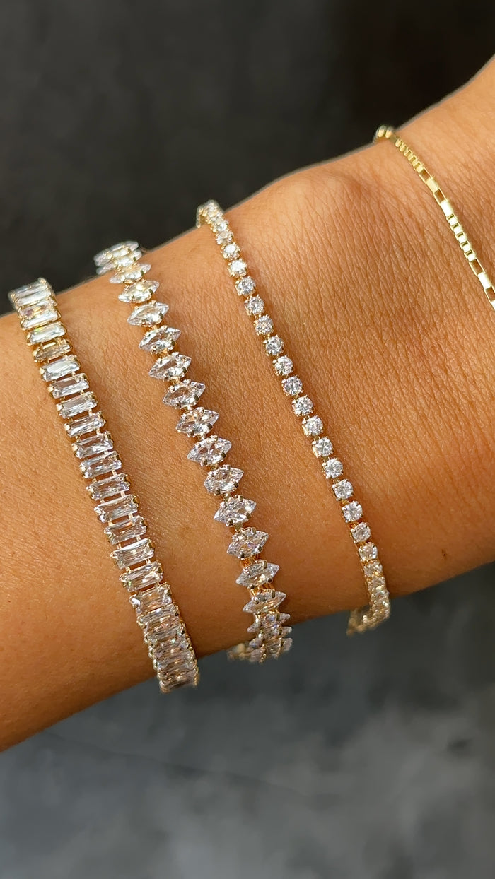Close up of a wrist with tennis bracelets on a black background