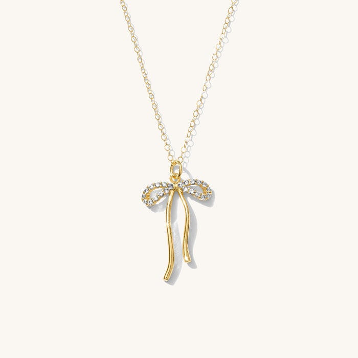 Close up of the gold Marlowe bow necklace on a white background
