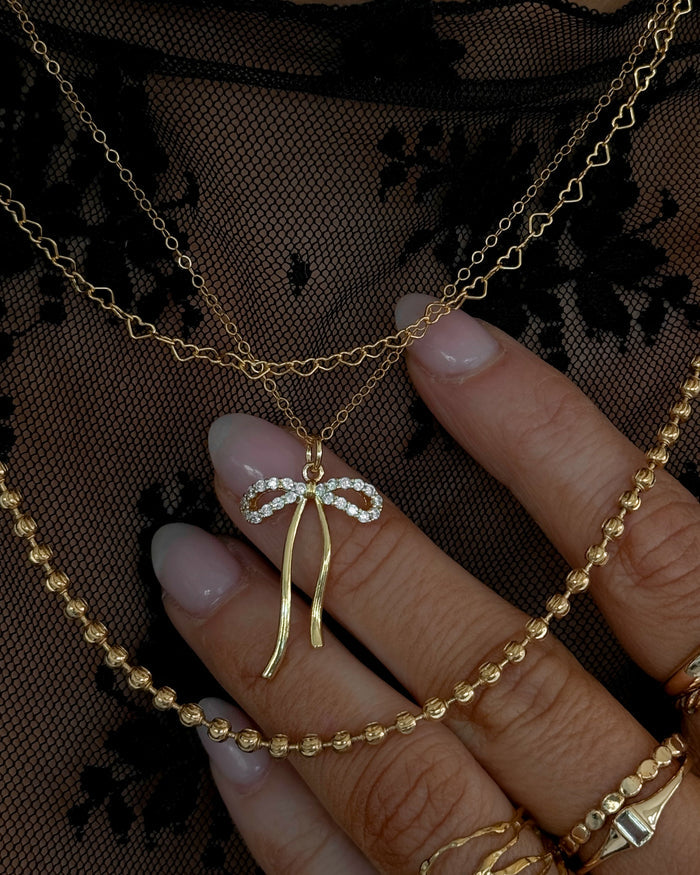 A model wearing the gold Marlowe bow necklace in a Beads by Tara campaign image