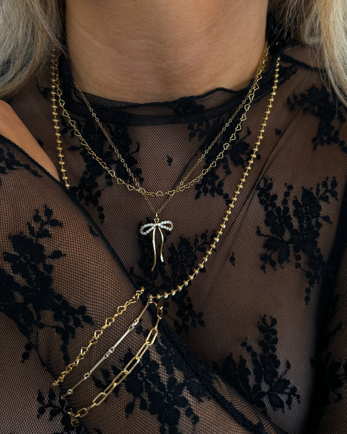 Campaign image of a model wearing the gold Marlowe bow necklace