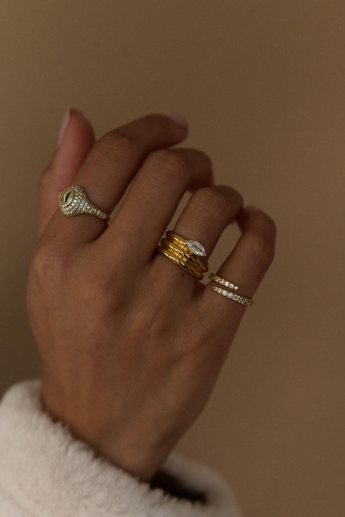Three polished gold bands meeting at a marquise cut centerpiece