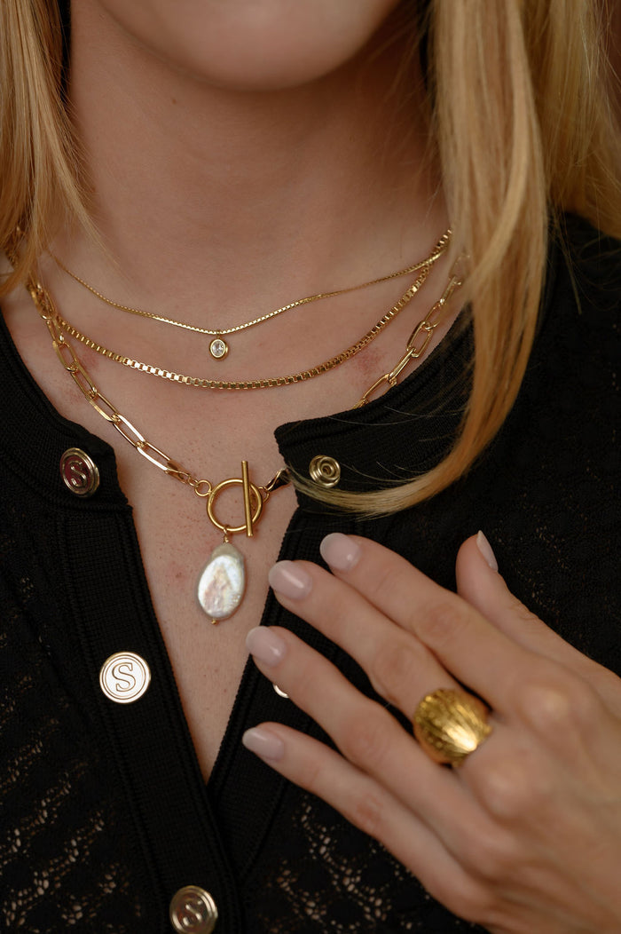 Detail view of the gold Martina herringbone necklace on a white background