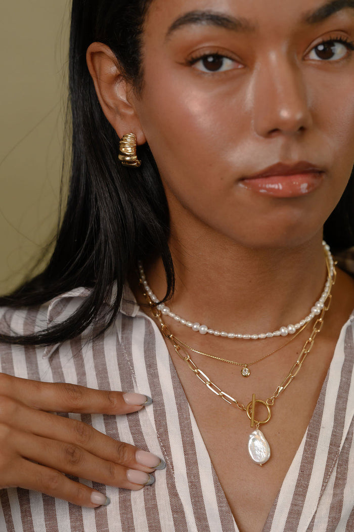 Close view of the gold Martina herringbone necklace on a white background
