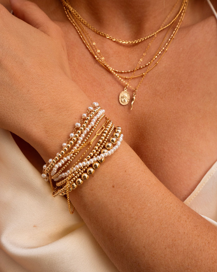 Dainty gold and pearl bracelet stack featuring the Maui bracelet