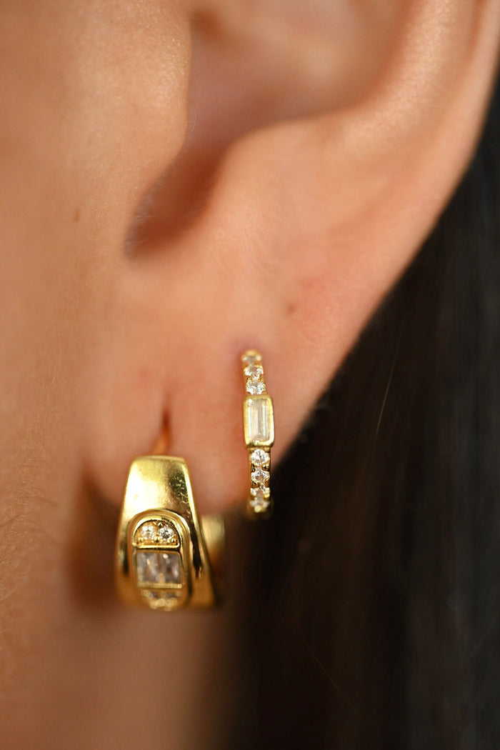 Close-up of gold hoop earrings worn by a person.
