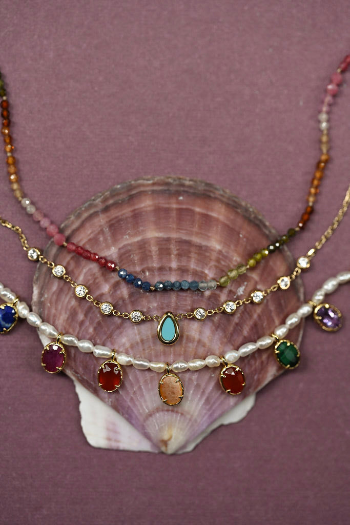 Stack of colorful necklaces on a shell with a purple background