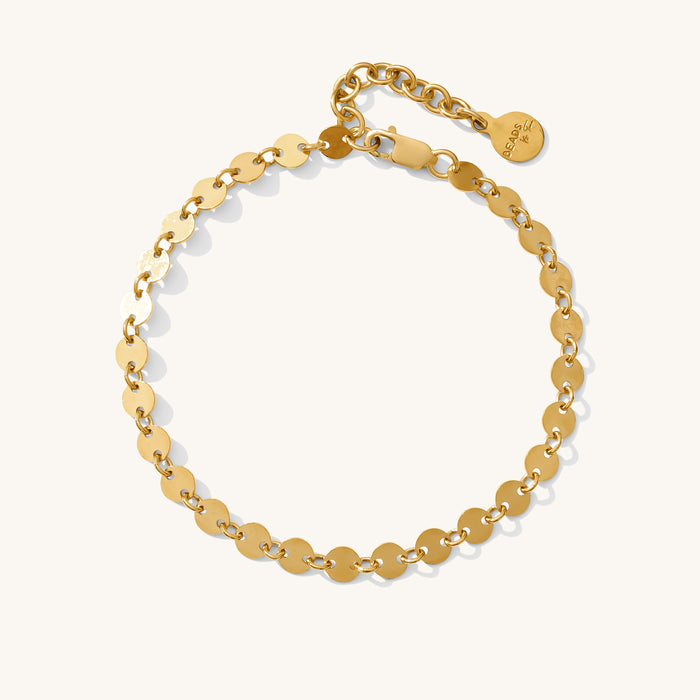 Close up of a gold bracelet with discs on a white background