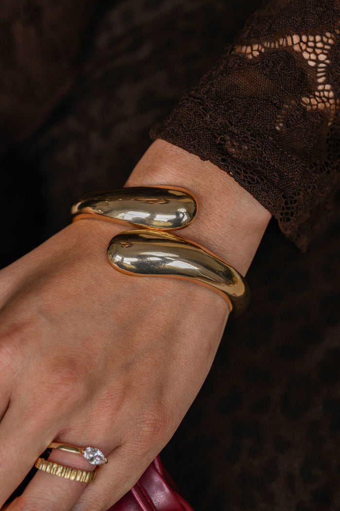 Gold bracelet on a wrist with a blurred background