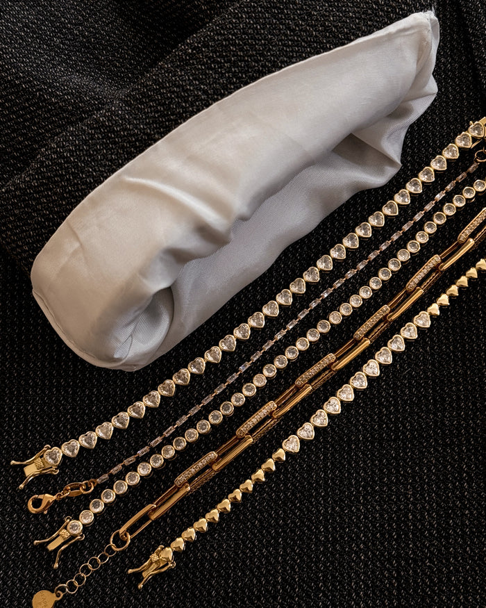 Close up of gold and stone bracelets on a black textured background