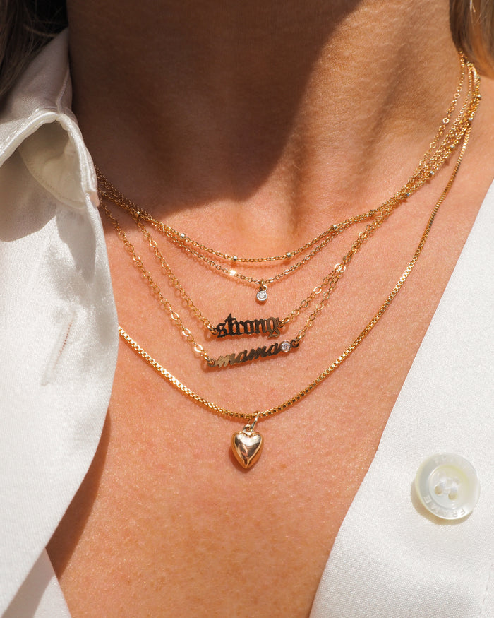 The gold mama necklace with a sparkling white topaz accent stone