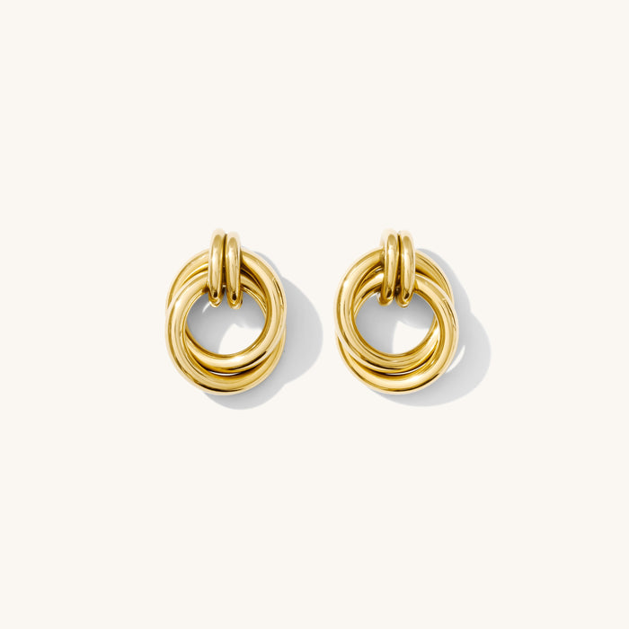 Close-up shot of gold circular knot studs on a white background