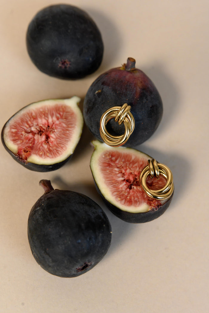 Close-up of figs, some cut in half showcasing a pair of statement earrings