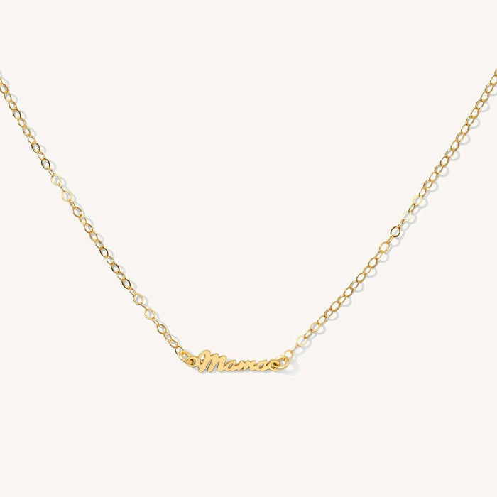 Close up of the gold mini mama necklace on a white background
