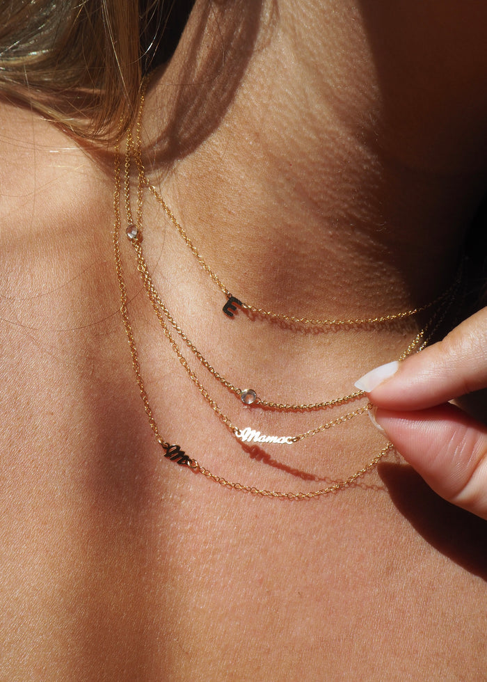 Close up of a neckline wearing the gold mini mama pendant necklace