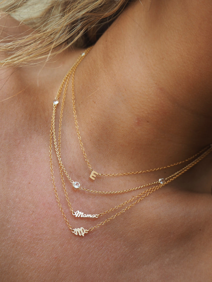 The gold mini mama necklace worn layered with dainty gold chains