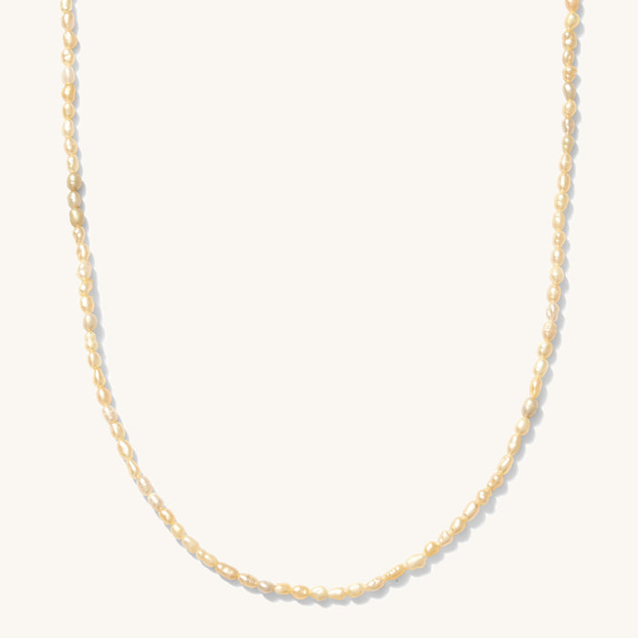 Close up of the gold Mini Pearl necklace on a white background