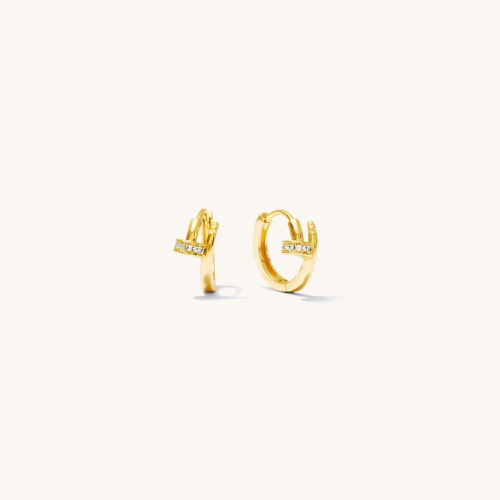 Close up of gold huggie earrings on a white background