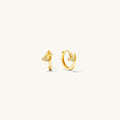 Close up of gold huggie earrings on a white background