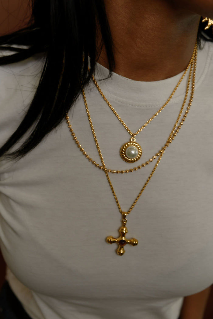 Detail view of the gold La Mer pearl pendant necklace on a white background