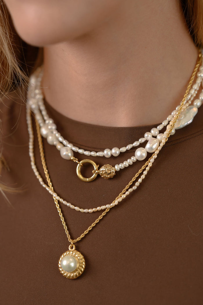 Close up of the gold La Mer pearl pendant necklace by Beads by Tara on a white background