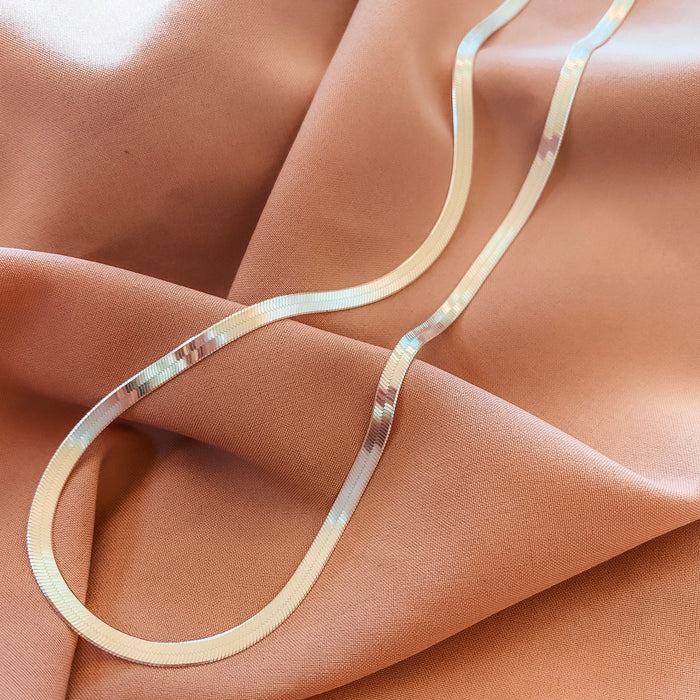 Close up of a neckline wearing the Nile herringbone chain in silver
