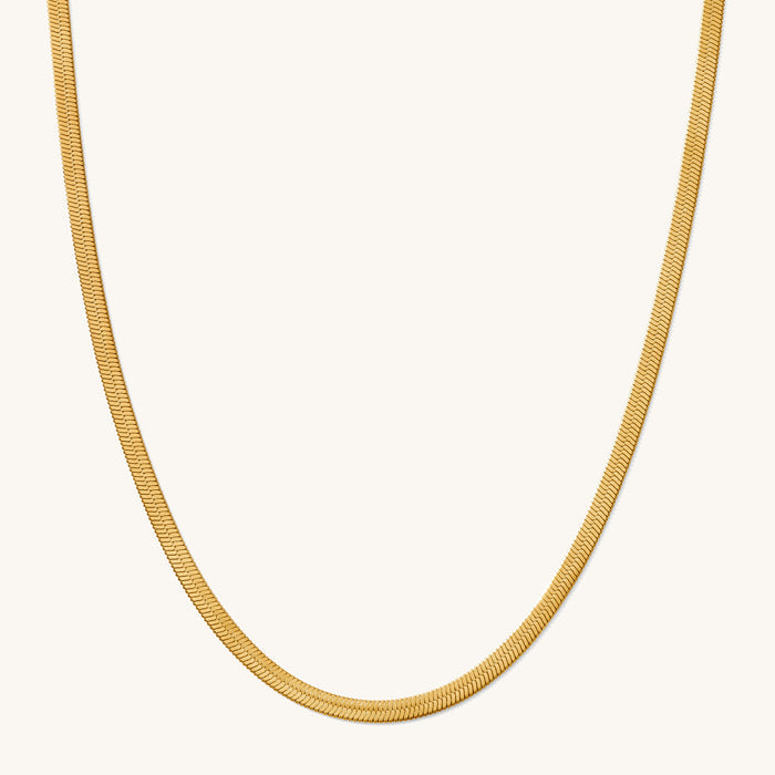 Close up of the gold Nile herringbone chain necklace on a white background