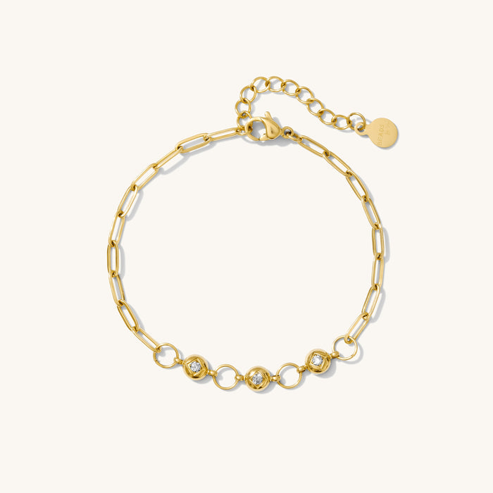 Close up of gold chain bracelet with stones on a white background