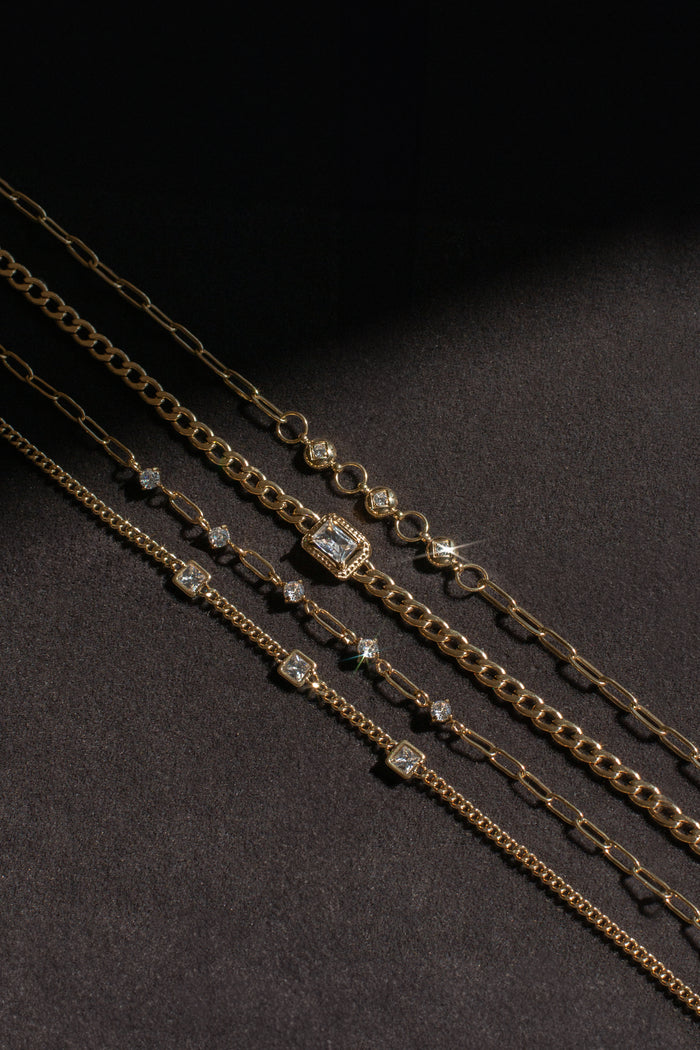 Gold bracelets with stone accents on a black background